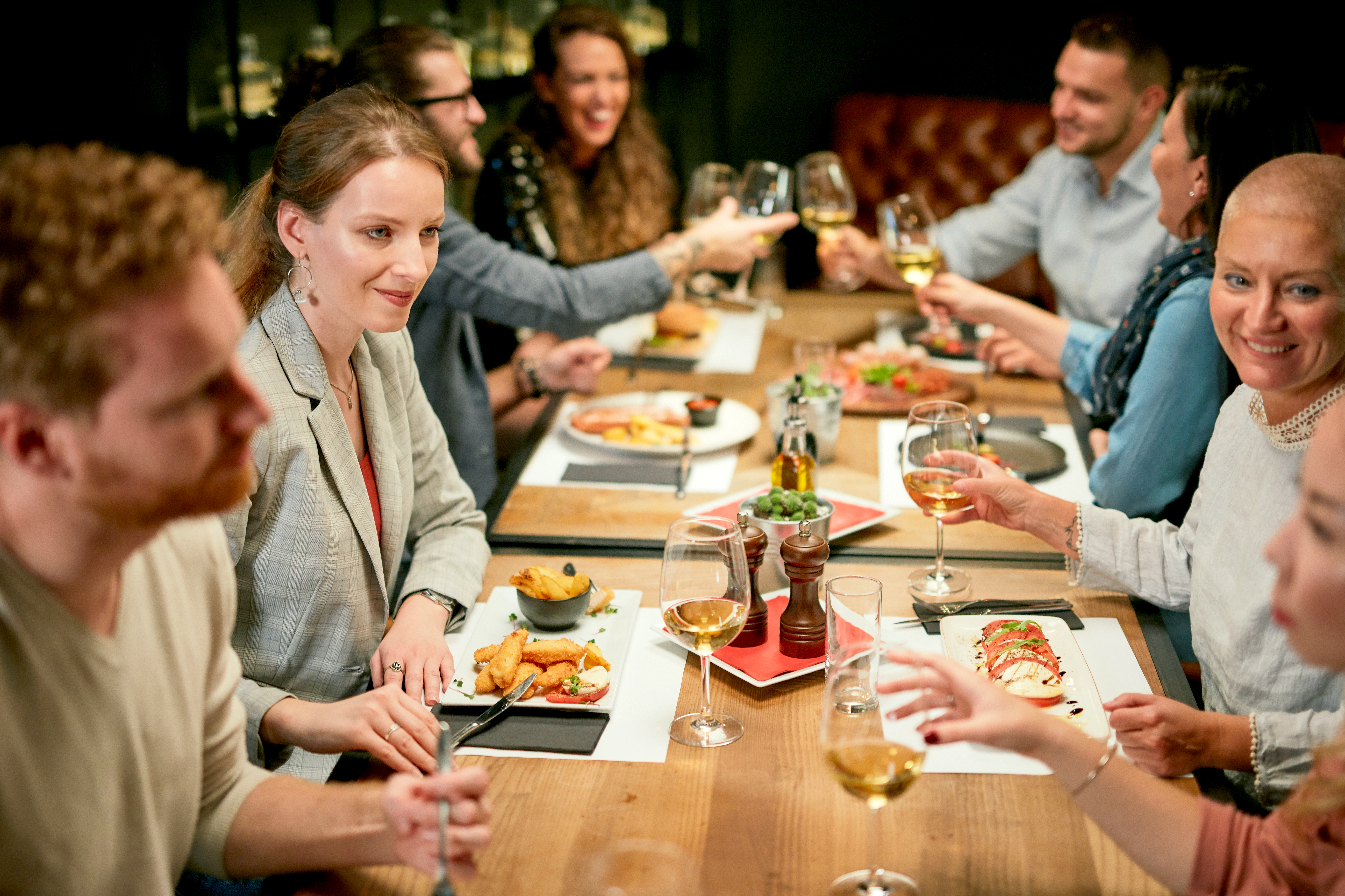 A group of professionals sit at a dinner table, networking