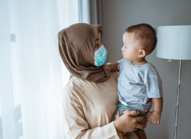 Woman in face mask holding toddler