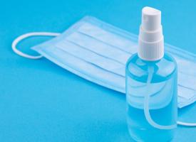 spray sanitiser and face mask on blue bench
