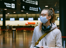 Woman wearing a surgical mask while travelling through airport