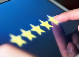 person selecting five star review on ipad