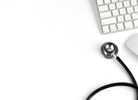 computer keyboard and stethoscope on white desk