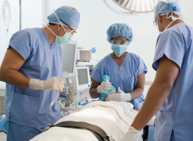 Doctors in scrubs looking over patient on operating table 