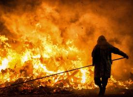 silhouette of fire fighter against large blaze 