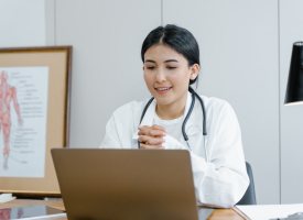 Female doctor in her consulting room talking to patient on lap top video 
