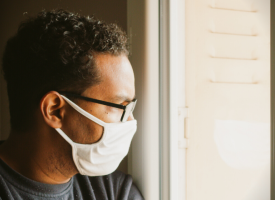 Man in mask looking out window