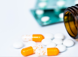 pills coming out of a bottle with pill pack in the background 