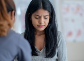 Young female doctor looking distressed with another doctor comforting 