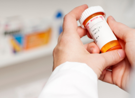 chemist's hand holding a pill bottle 