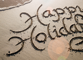 happy holidays written in sand