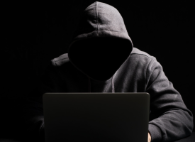 Dark hooded figure on computer