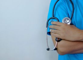 Doctor in blue scrubs holding a stethoscope