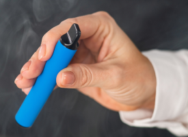 Woman's hand holding a blue disposable vape