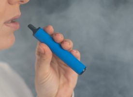 Woman using a disposable blue vape pen