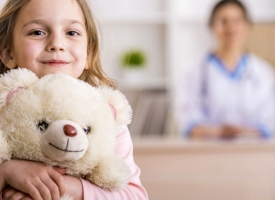 Image of happy young girl with teddy bear in medical practice