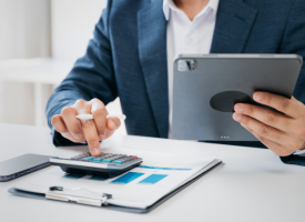 Man using calculator and a tablet at a desk