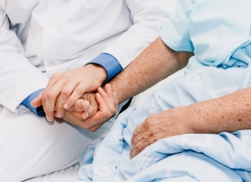 Close up of a doctor holding a patient's hand.