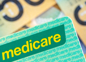 A green Medicare card on a background of $50 Australian notes.