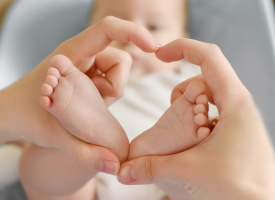 A baby's feet held by a pair of woman's hands, making a heart shape.