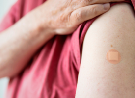 Man lifting shirt sleeve to reveal a plaster on his arm where he received a vaccine