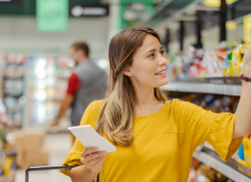Woman shopping in supermarket aisle, looking at packaged food