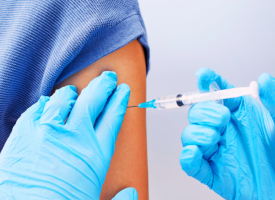 Gloved hands giving vaccination to arm