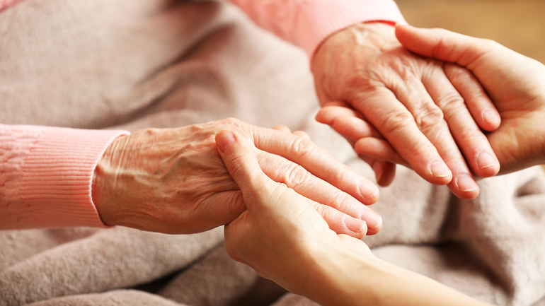 Young person holding the hands of an elderly person