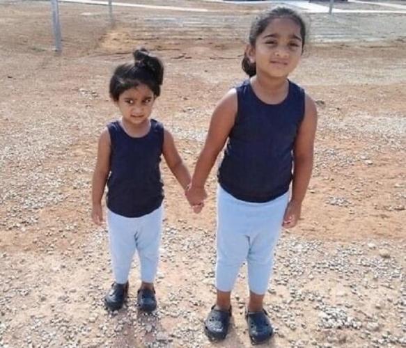 Five year old Kopika Murugappan and her sister Tharunicaa in a detention centre yard 