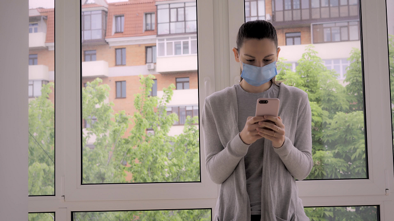 Woman using phone while wearing face mask