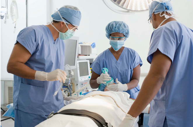 Doctors in scrubs looking over patient on operating table 
