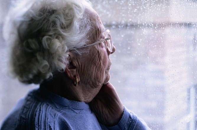senior woman looking out window 