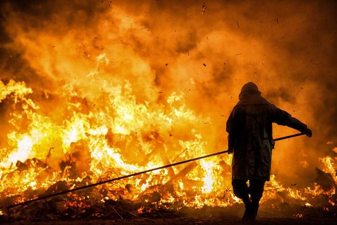 silhouette of fire fighter against large blaze 