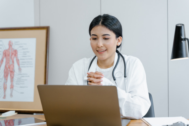 Female doctor in her consulting room talking to patient on lap top video 