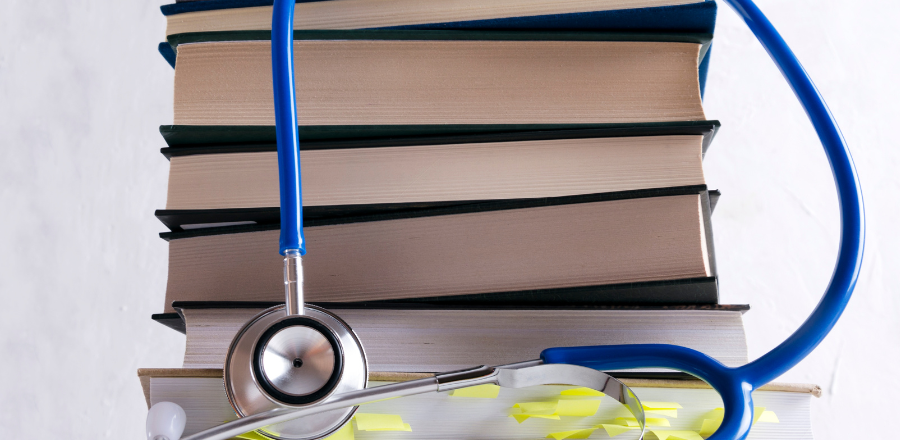 medical books with stethoscope draped over 