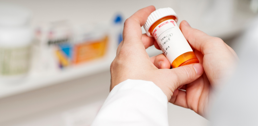 chemist's hand holding a pill bottle
