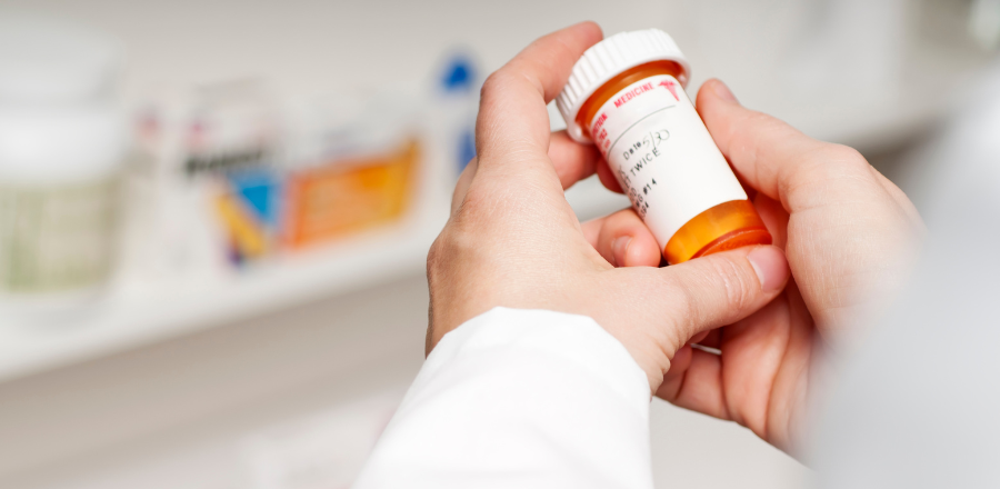 chemist's hand holding a pill bottle 