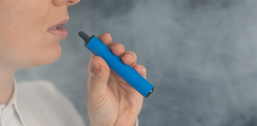 Woman using a disposable blue vape pen