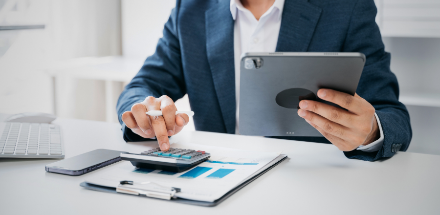 Man using calculator and a tablet at a desk