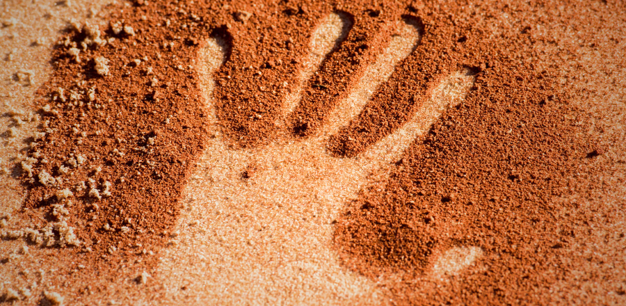 Hand shape on sand, in the style of Indigenous art