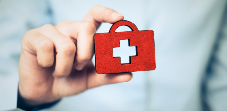 Hand holding a small symbol of a briefcase and a health cross